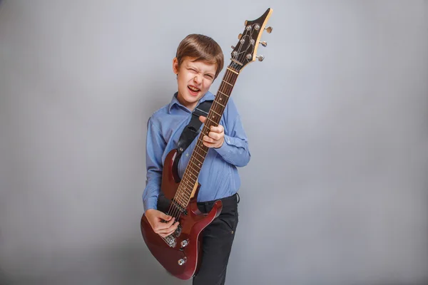 Boy playing guitar on gray background — Stock Photo, Image