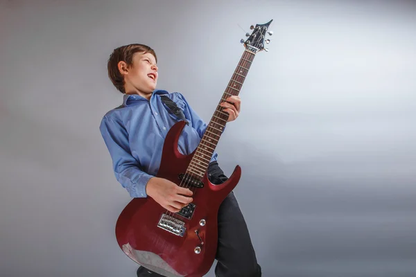 Boy teenager European appearance brown emotionally plays guitar — Stock Photo, Image