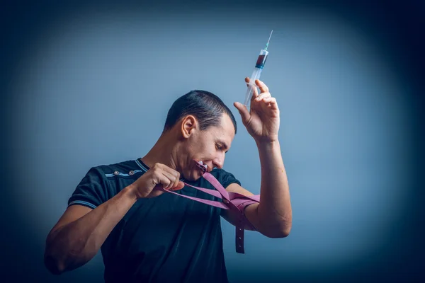 Maschio di aspetto europeo tiene i denti laccio emostatico e iniettato — Foto Stock