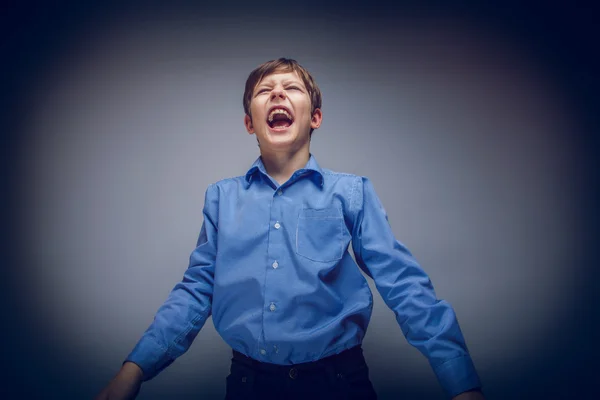 Portrait of a boy brown European appearance shouting on gray bac — Stock Photo, Image