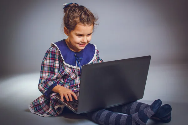 Teen girl 5 years of European appearance sitting looking at a la — Stock Photo, Image