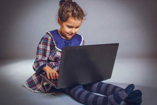 Tiener meisje speelt Europees uiterlijk 5 jaar laptop zitting op — Stockfoto