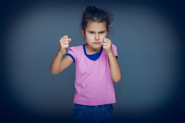 Teenie-Mädchen zeigt wütende Fäuste auf grauem Hintergrund Kreuzprozess — Stockfoto