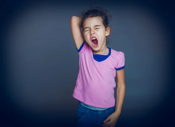 Teen girl yawns sleepy opened her mouth on a gray background cro — Stock Photo, Image