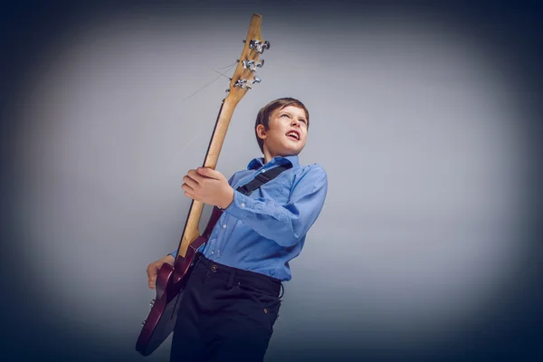 Teenager boy brown European appearance playing guitar cross proc — Stock Photo, Image