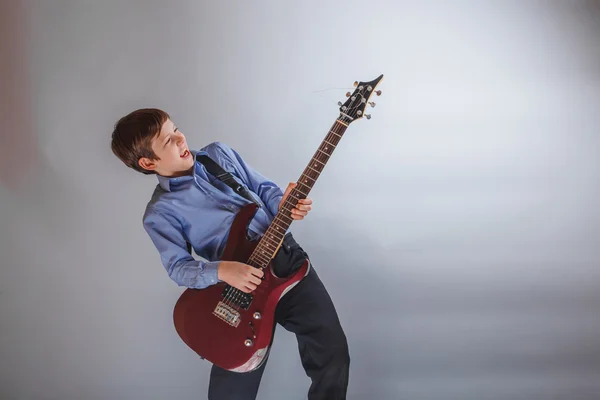 Adolescente chico marrón pelo europeo apariencia jugando guitarra en un — Foto de Stock