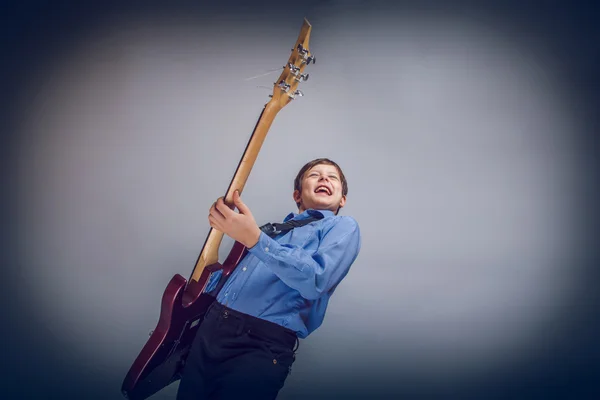 Adolescente ragazzo capelli castani di aspetto europeo suonare la chitarra fe — Foto Stock