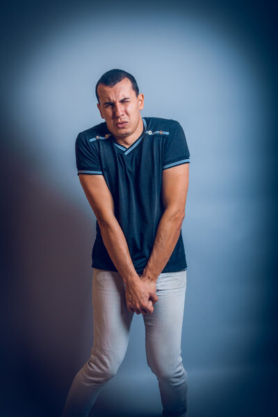 man of European appearance brunet holding hands on the abdom