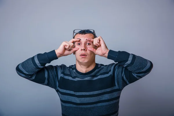 Europese uitziende man van 30 jaar opende ogen met zijn handen op een — Stockfoto