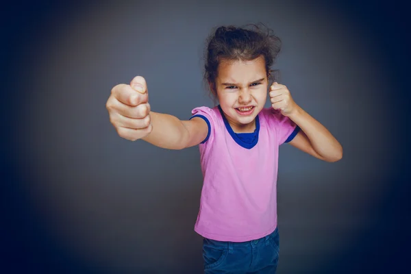 Girl getting angry fist shows on gray background cross process — Stock Photo, Image