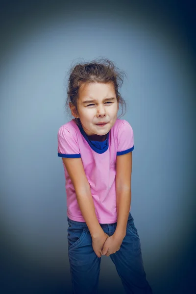 Ragazza bambino vuole usare il bagno su uno sfondo grigio croce pr — Foto Stock