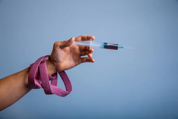 Hand with plait holding syringe drug on gray — Stock Photo, Image
