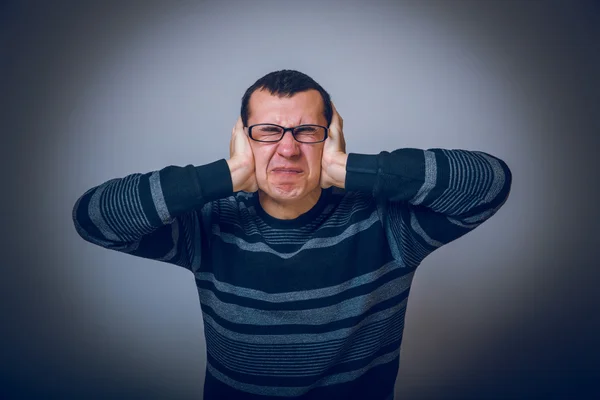 Europeu de aparência masculina cobrindo seus ouvidos com as mãos morena — Fotografia de Stock