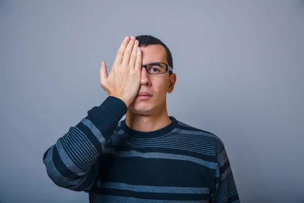 European-looking male put his hand over half of the face on a gr — Stock Photo, Image