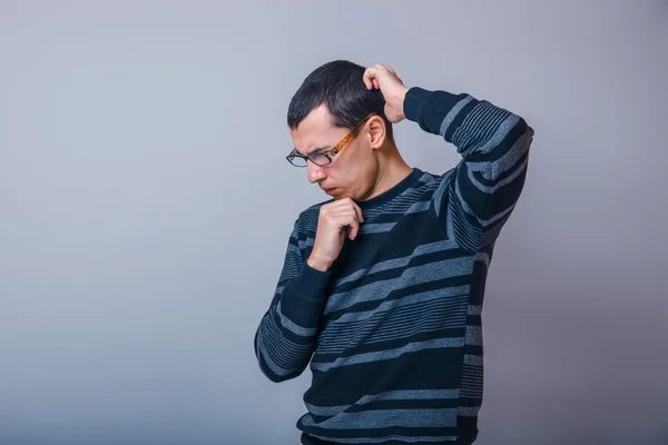 Male of European appearance brunet thinking on a gray background — Stock Photo, Image