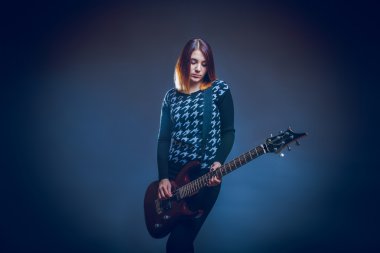 Avrupa görünümlü kız gri bir arka plan üzerinde gitar çalmak