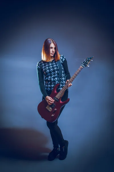 Europäisches Aussehen braune Haare Mädchen spielt Gitarre auf einem grauen Bac — Stockfoto