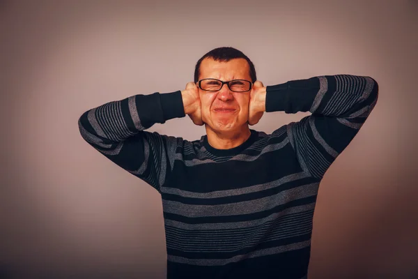 Evropská vypadající muž třicet let, kryje uši s jeho h — Stock fotografie