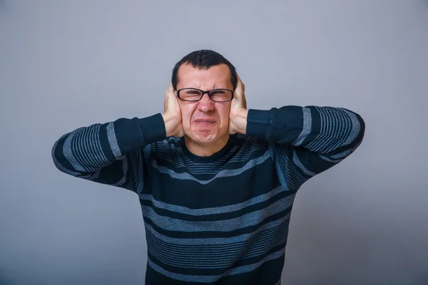 Europeiska-ser man som täcker öronen med hans händer brunet — Stockfoto