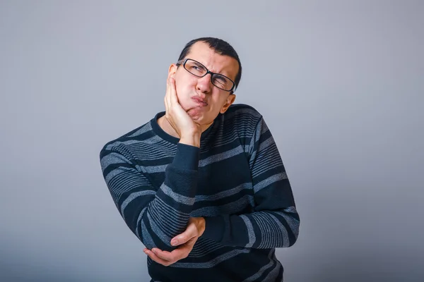 European-looking male put his hand to his cheek wrinkled his fac — Stock Photo, Image