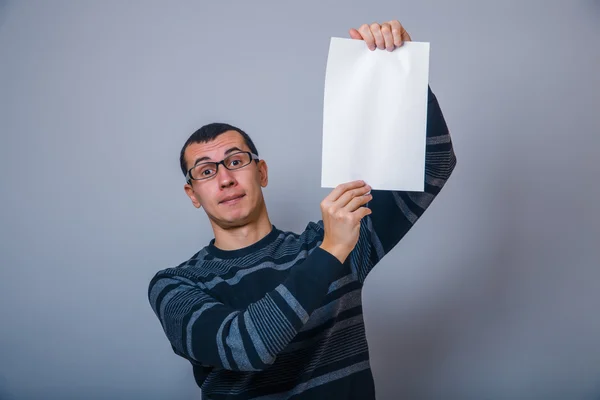 Europese uitziende man met een wit vel papier op een grijze b — Stockfoto