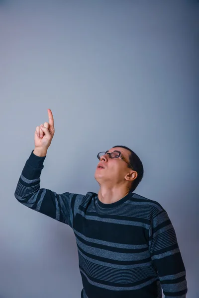 Male of European appearance brunet shows his hand up on a gray b — Stock Photo, Image