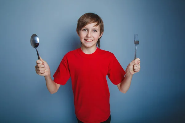 Jongen tiener Europese verschijning in een rood shirt houden een lepel — Stockfoto