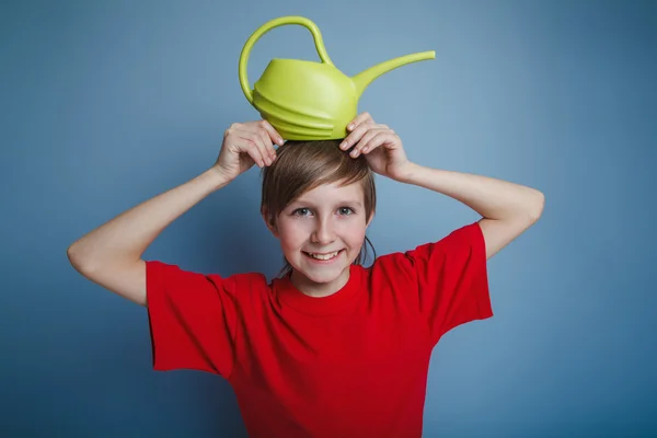 Boy teenager European appearance in a red shirt yellow watering — Stock Photo, Image
