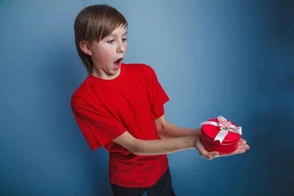 European -looking  boy of ten  years  holding a gift box on a gr — Stock Photo, Image
