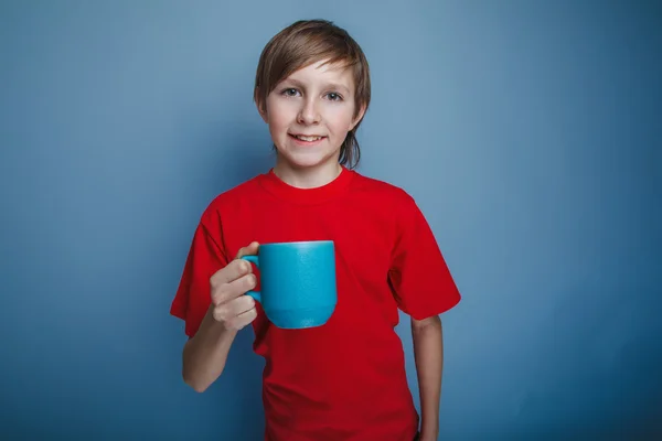 Aspetto europeo ragazzo adolescente in camicia rossa con una tazza blu — Foto Stock