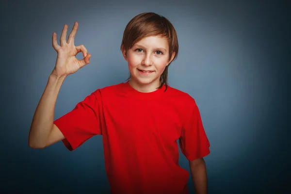 European-looking boy of ten years thumbs up gesture okay on a gr — Stock Photo, Image