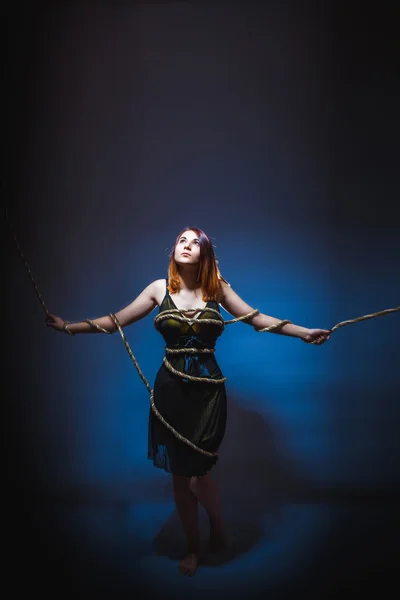 Girl of European appearance in dress hands tied with rope on a g — Stock Photo, Image