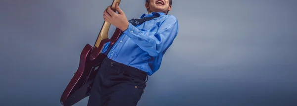 Adolescente ragazzo capelli castani di aspetto europeo suonare la chitarra fe — Foto Stock