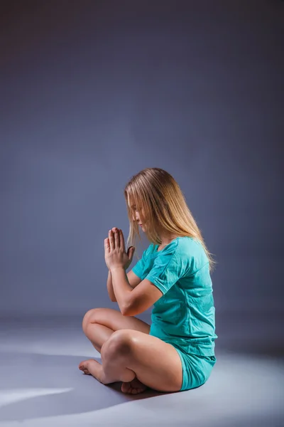 Girl blonde European appearance in a blue tracksuit meditates on — Stock Photo, Image