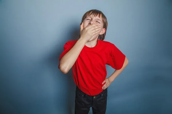 European-looking boy of ten years wants to sleep, yawning on gra — Stock Photo, Image