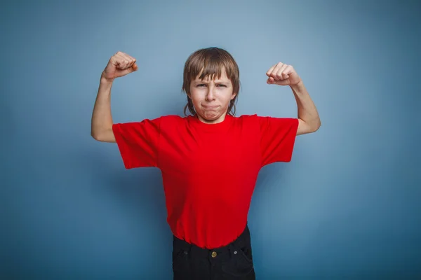 Boy teenager European appearance in a red shirt shows the power — Stock Photo, Image