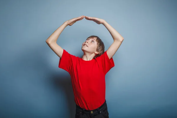 Boy teenager European appearance in a red shirt folded his arms — Stock Photo, Image