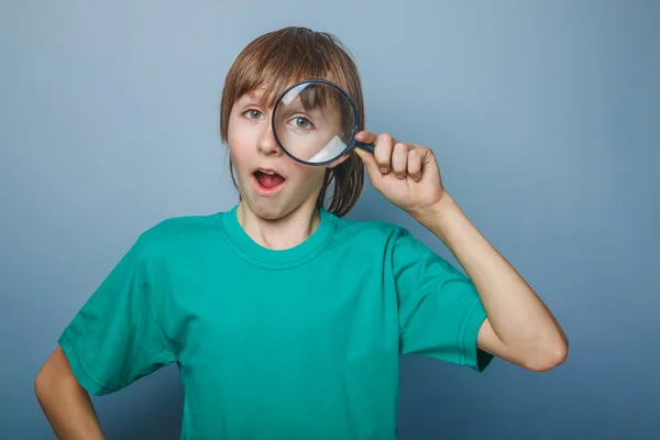 Ragazzo dall'aspetto europeo di dieci anni uno scherzo, guardando attraverso una ma — Foto Stock