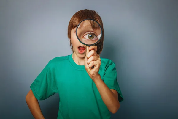 European-looking boy of ten years a joke, looking through a magn — Stock Photo, Image