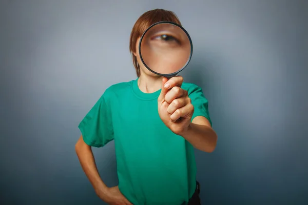 Europeiska-ser pojke på tio år tittar genom en magnifyin — Stockfoto