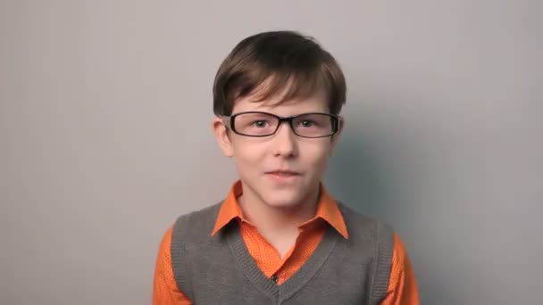 Adolescente chico divertido risas tiró hacia atrás un su cabeza con gafas diez años en un fondo gris — Vídeo de stock