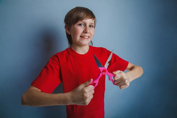 Ragazzo, adolescente, dodici anni in camicia rossa è in possesso di un paio di — Foto Stock