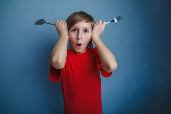 Teenager  in red shirt boy twelve years holding  spoon and fork, — Stock Photo, Image