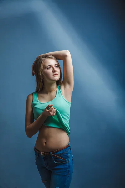 Mujer en pantalones vaqueros azules en una camisa verde mirando hacia otro lado —  Fotos de Stock