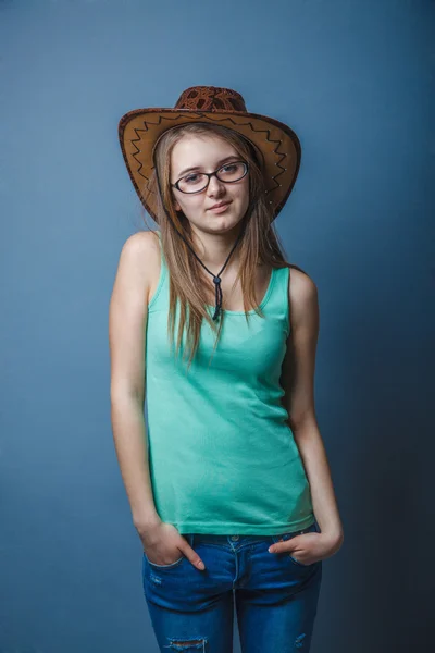 Mujer en pantalones vaqueros azules en una camiseta verde con sombrero mirando a la s —  Fotos de Stock