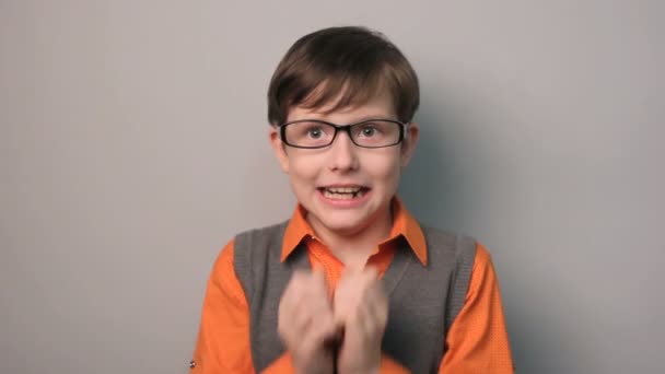 Niño manos a su boca miedo gafas de choque diez años sobre fondo gris — Vídeos de Stock