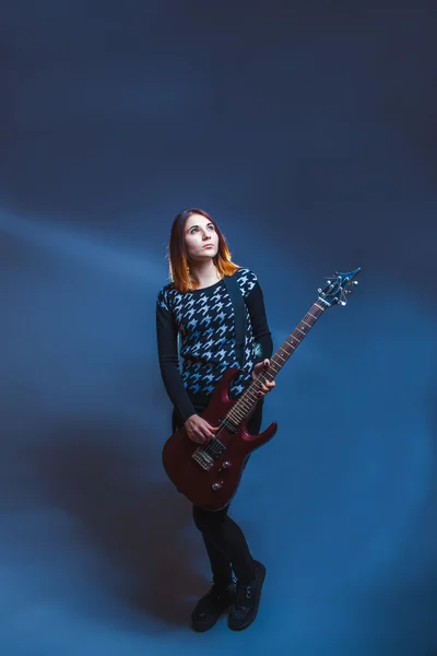 European-looking girl in a sweater holding a guitar and looking — Stock Photo, Image