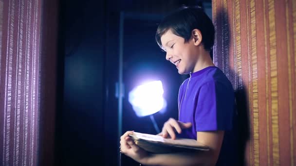 Genç çocuk çocuk daire sayfa saygısız olarak duvara karşı duran bir kitap okur — Stok video