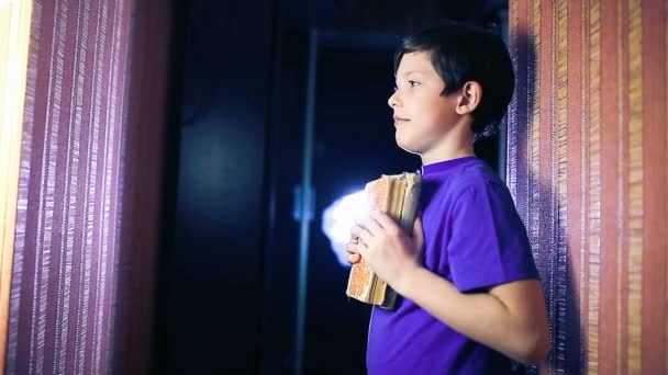 Adolescente menino criança lendo um livro, sim gesto de pé contra a parede no apartamento página lançando — Vídeo de Stock