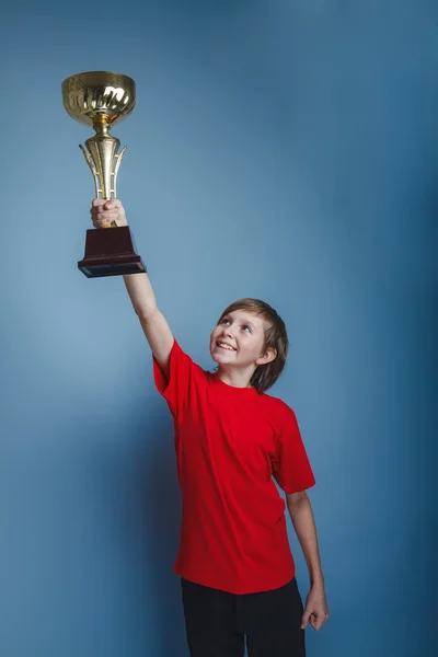 Boy teenager European appearance in a red shirt lifted the cup i — Stock Photo, Image